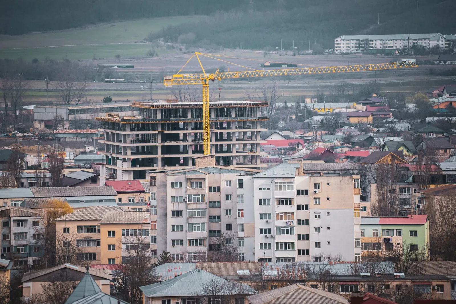 View of a city construction site with a prominent tower crane and surrounding buildings. Stock photo illustrating Shraddha Prime Projects' fund raise story.
