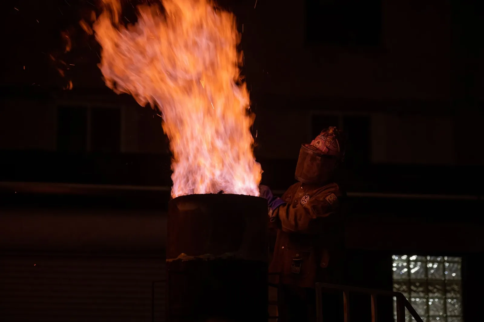 An industrial worker in protective gear handles a large torch flame at night. Stock photo illustrating SK Minerals & Additives' new order story.