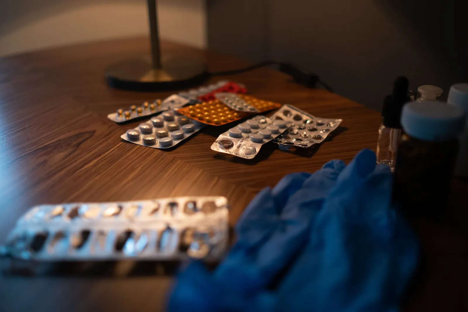 Close-up of various medication blister packs and gloves on a wooden table, signifying health and recovery. Stock photo illustrating Alkem Laboratories' product launched story.
