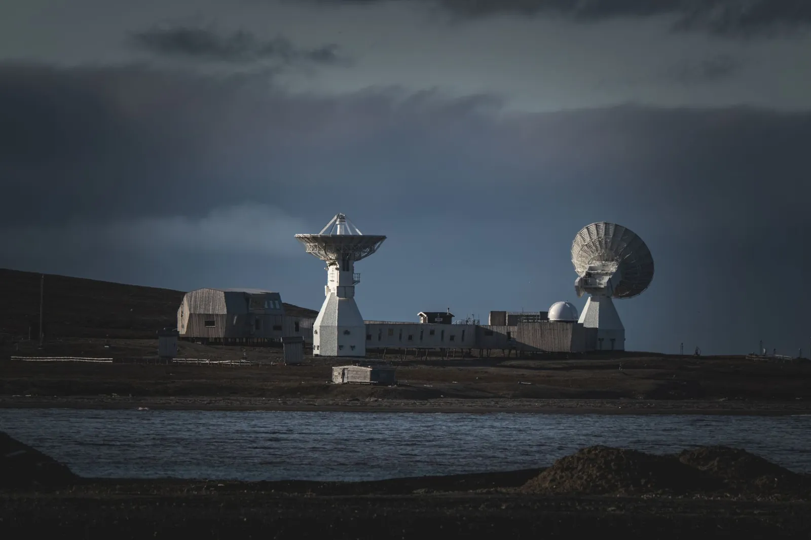 A remote satellite station with large dishes stands under a moody dark sky by the water. Stock photo illustrating Avantel's new order story.