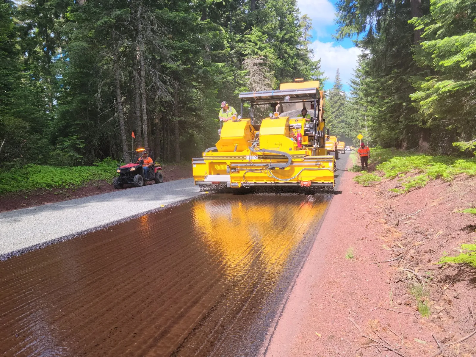 Paving machine working on a road through Mount Hood forested area. Stock photo illustrating Brahmaputra Infrastructure's new order story.