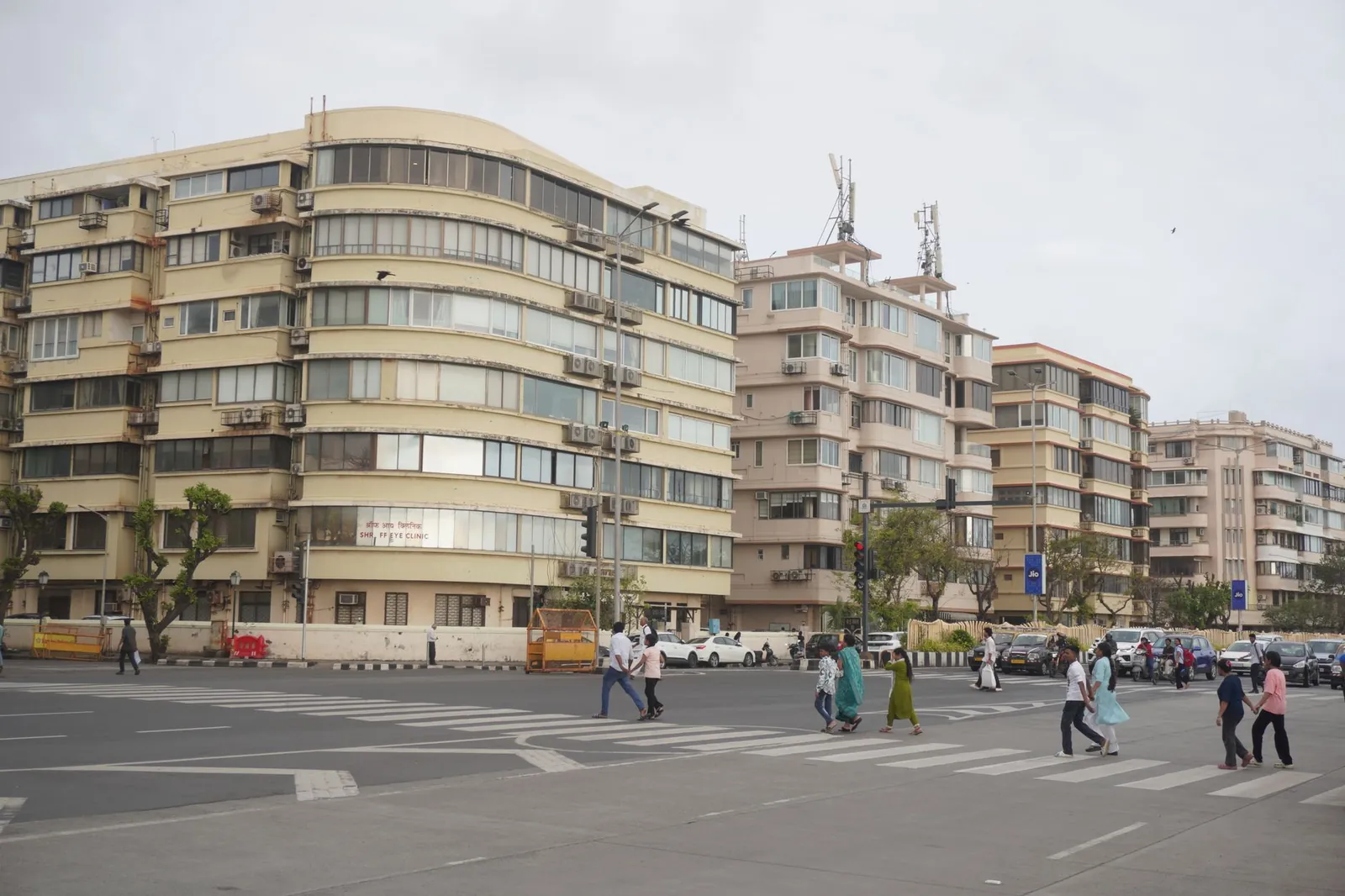 People crossing a street in Mumbai with iconic apartment buildings in the background. Stock photo illustrating Modis Navnirman's new order story.
