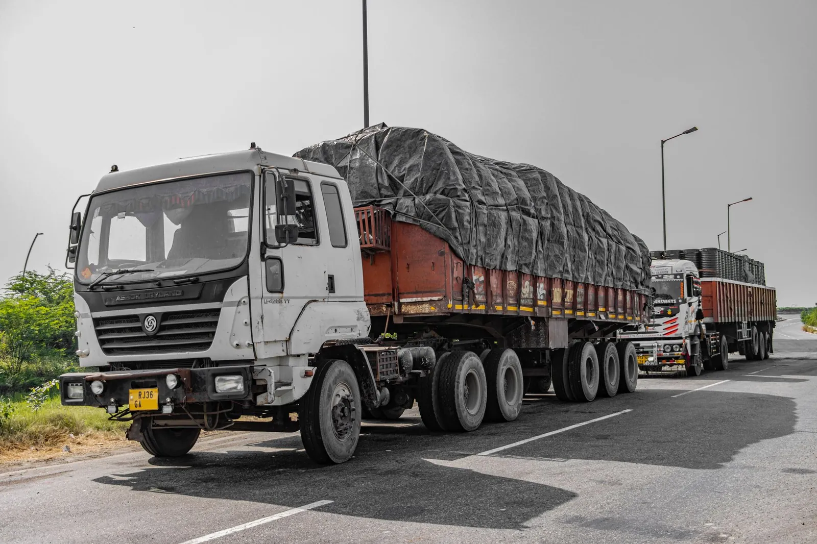 Heavy cargo trucks parked on a highway in Deeg, Uttar Pradesh, India, showcasing Indian logistics. Stock photo illustrating Ravindra Energy's expansion story.
