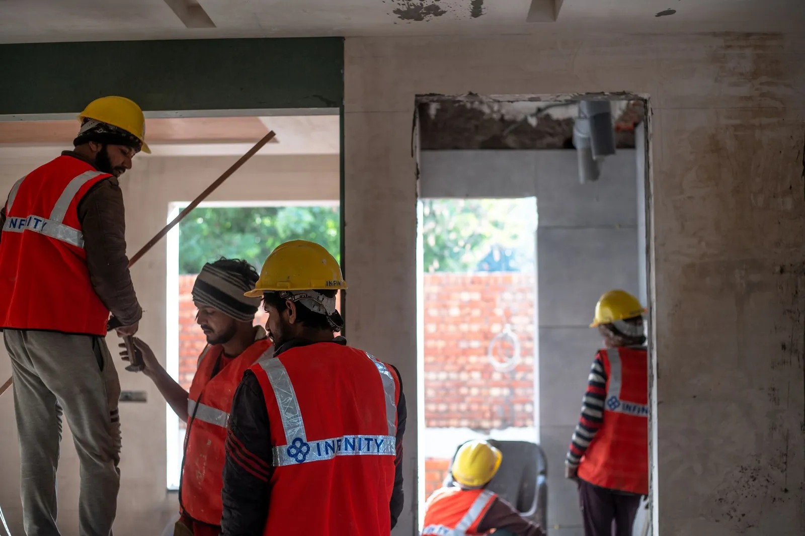 Construction workers wearing safety gear at an indoor building site in Delhi. Stock photo illustrating Telge Projects' fund raise story.