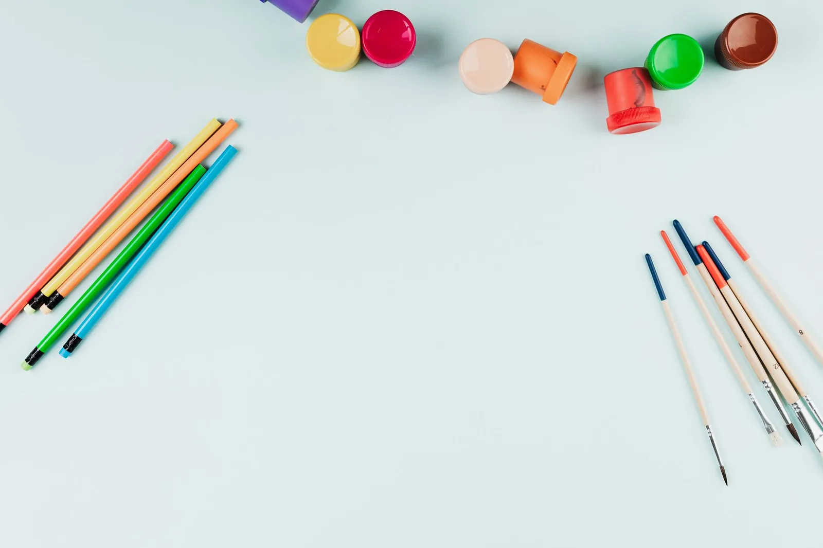 Flat lay of colorful art supplies, pencils, and brushes on a light background with copy space. Stock photo illustrating DOMS Industries' earning call story.