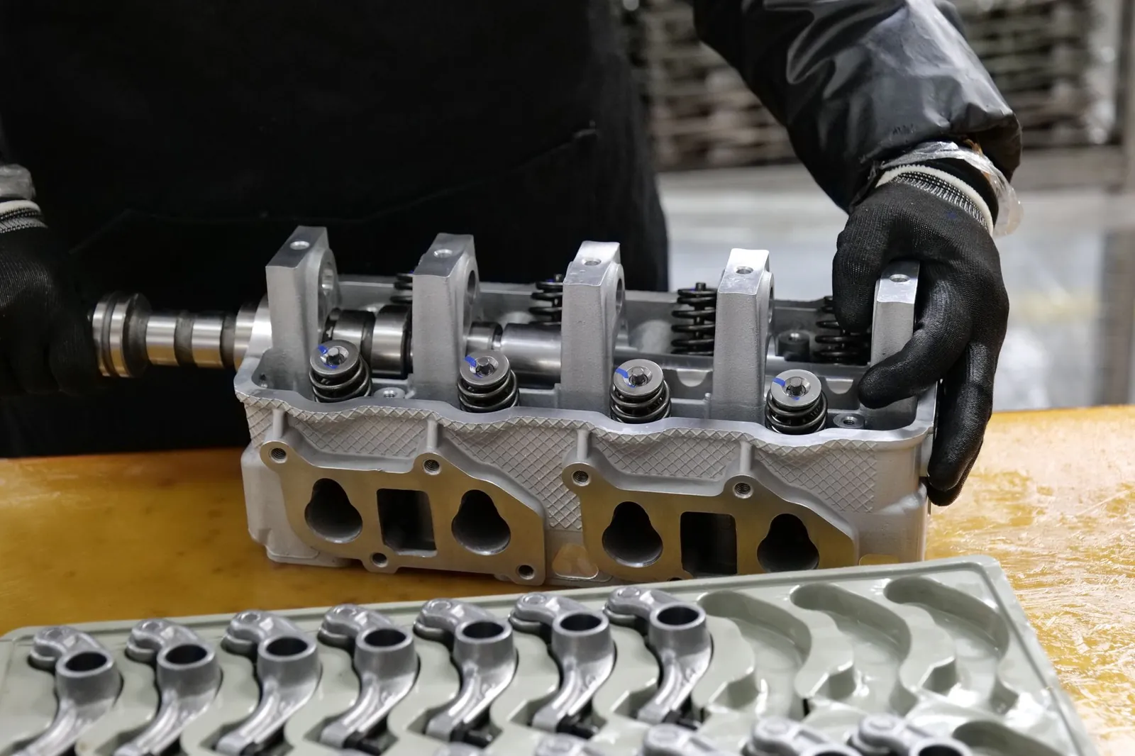 Mechanic assembling an engine cylinder head with precision components on a workbench. Stock photo illustrating Sigma Advanced Systems' new order story.