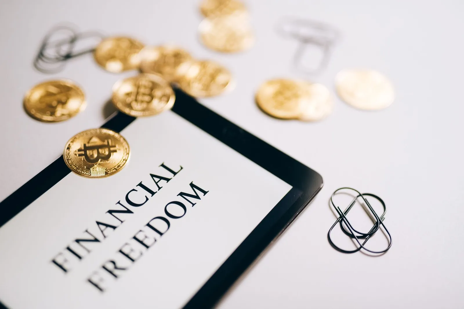 Close-up of Bitcoin coins and an iPad displaying 'Financial Freedom,' symbolizing modern digital savings. Stock photo illustrating OnEMI Technology Solutions' financial results story.