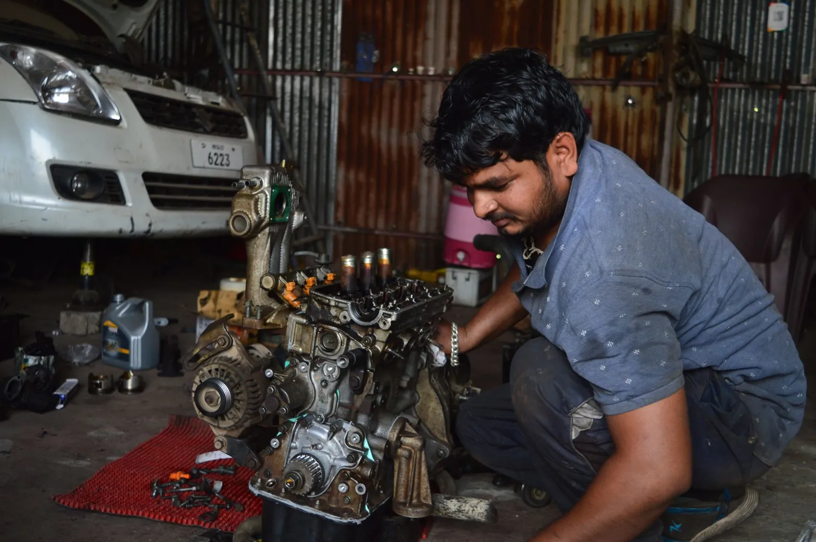 A mechanic works on an engine in a garage in India, showcasing auto repair skills. Stock photo illustrating Kross' financial results story.