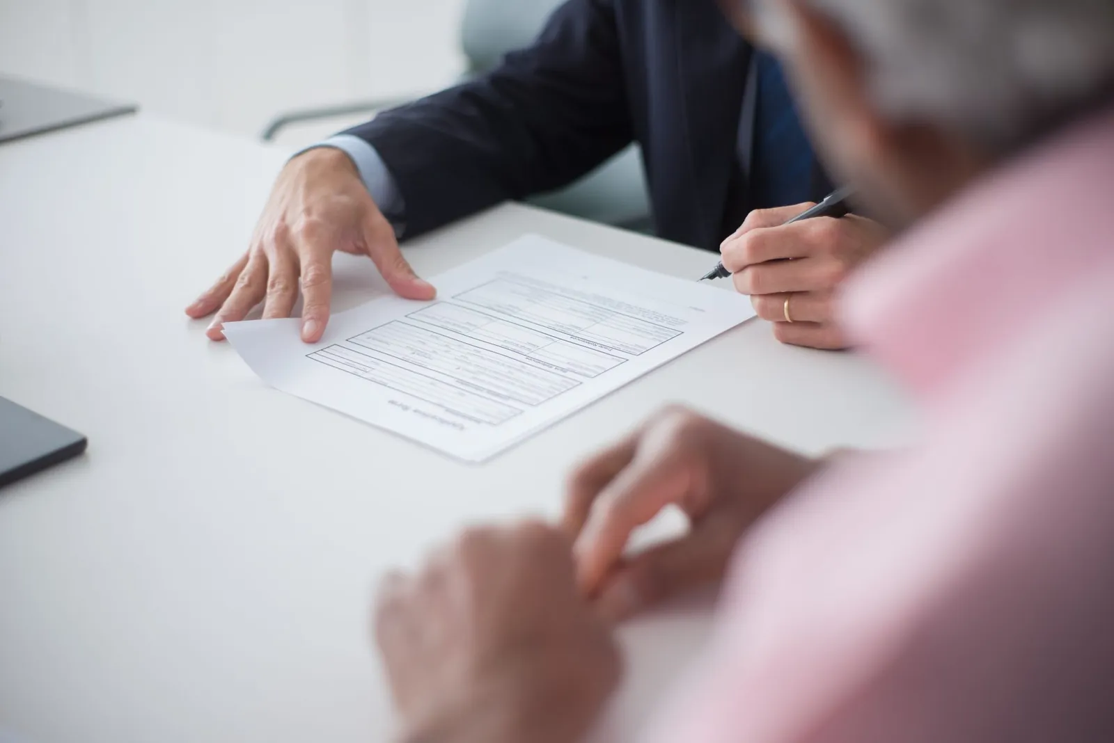 Two professionals engaging in a business meeting, signing documents for a consulting agreement. Stock photo illustrating Manba Finance's fund raise story.