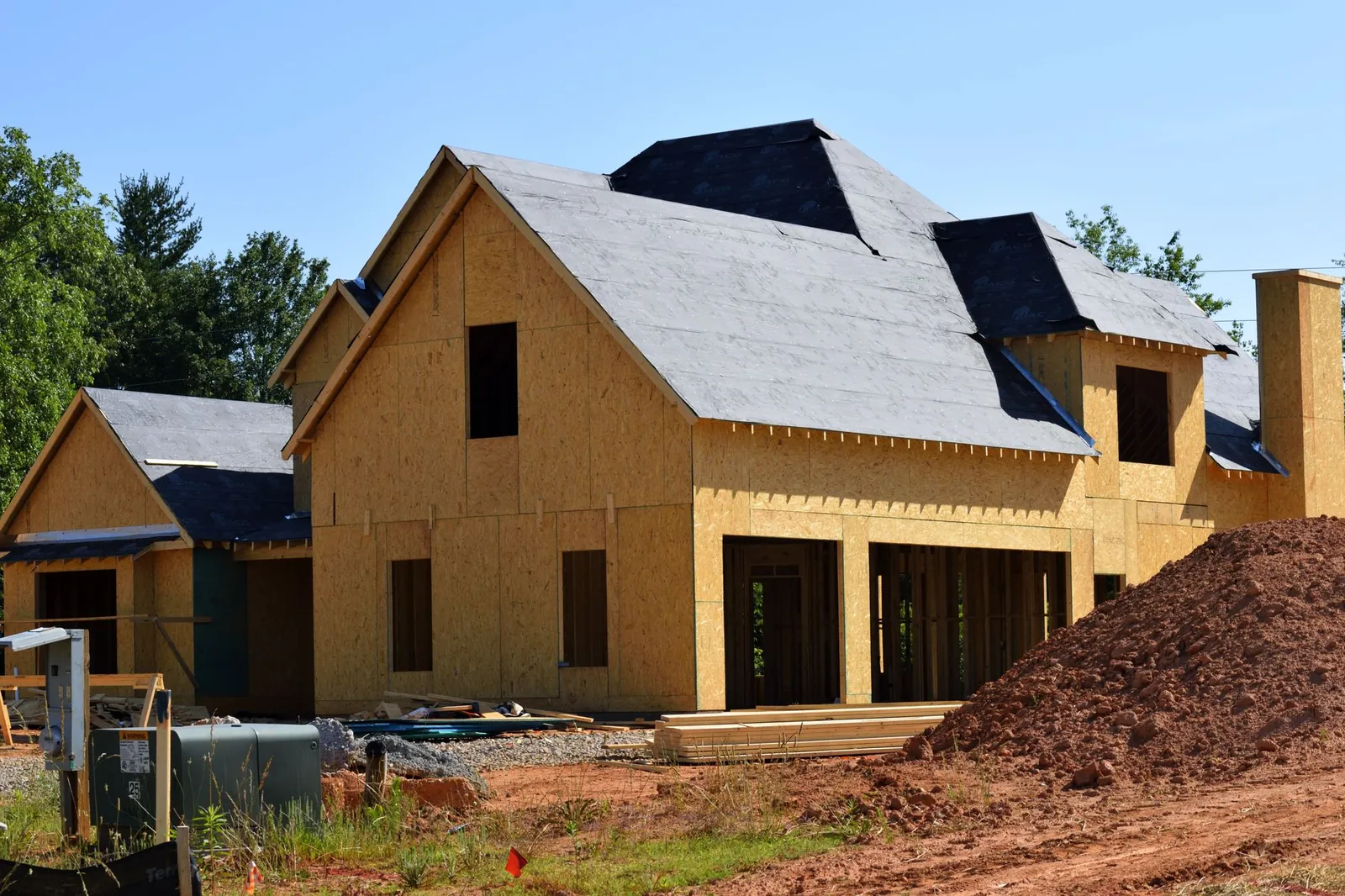 A partially built wooden house under construction, showcasing its progress and design in daylight. Stock photo illustrating Oberoi Realty's fund raise story.