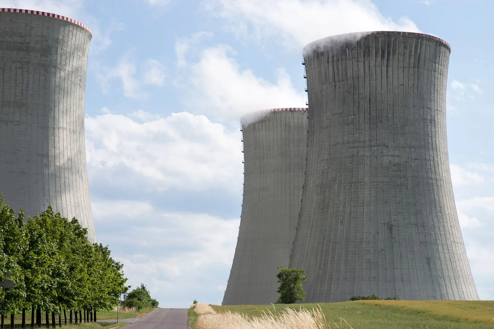Cooling towers of Dukovany nuclear power plant with steam on a clear day. Stock photo illustrating GEE's earning call story.