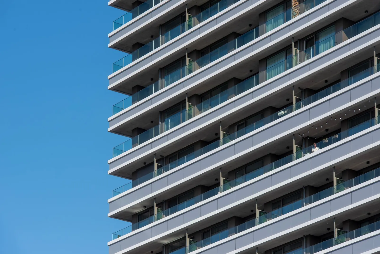 Contemporary high-rise apartment exterior with balconies and blue sky background. Stock photo illustrating Oberoi Realty's product launched story.