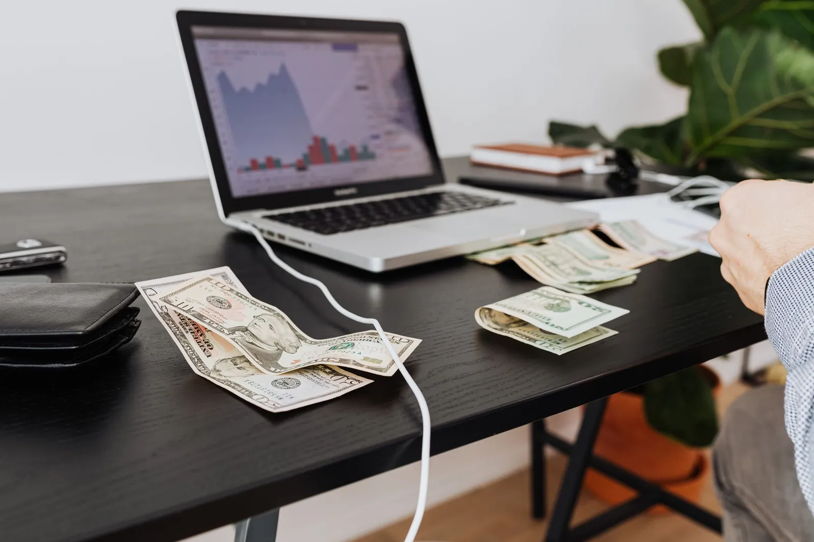 A workspace with cash, laptop, and financial graph showing investment analysis. Stock photo for the ALFA News guide: Cash Flow vs Profit: A Guide to SEBI Financial Disclosures.