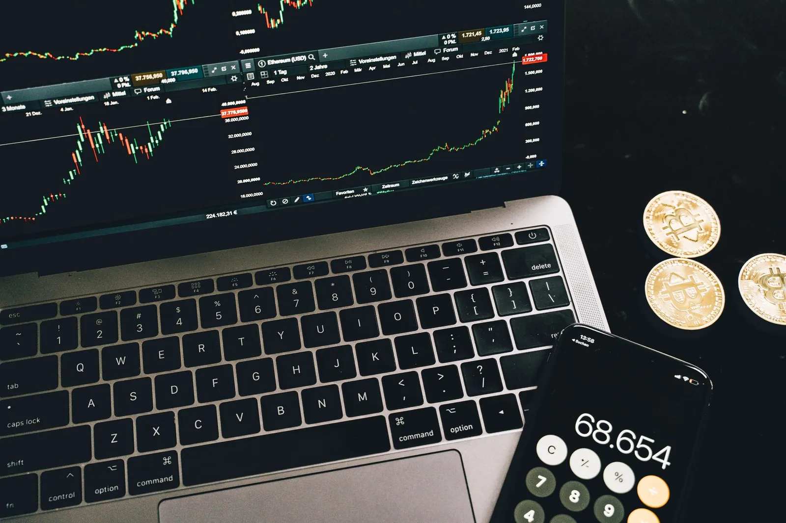 A laptop with trading charts, smartphone calculator, and bitcoin coins depicting cryptocurrency trading. Stock photo illustrating Akiko Global Services' earning call story.