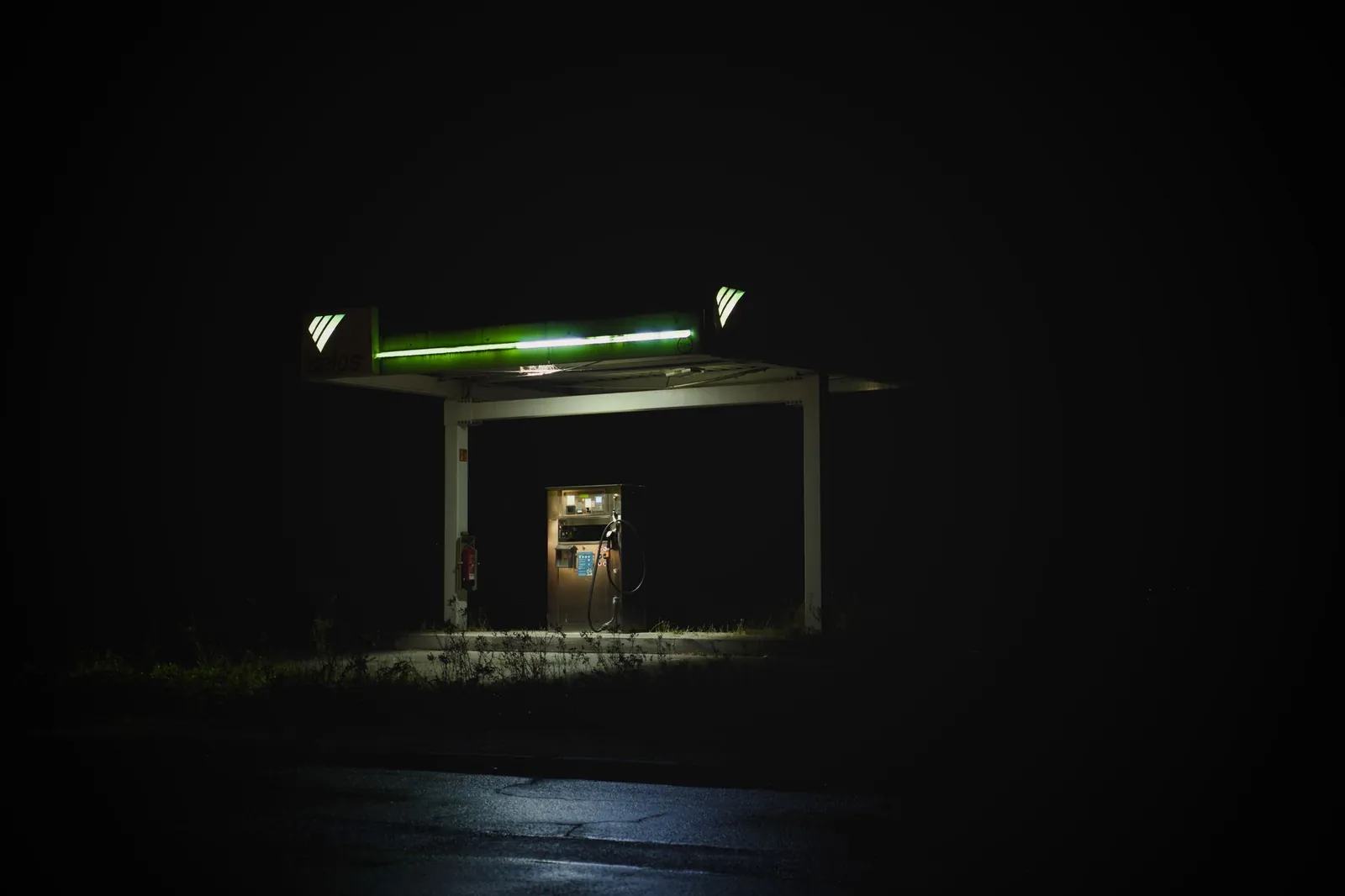 Isolated gas station glowing at night against a dark background, creating a mysterious vibe. Stock photo illustrating GAIL (India)'s fund raise story.