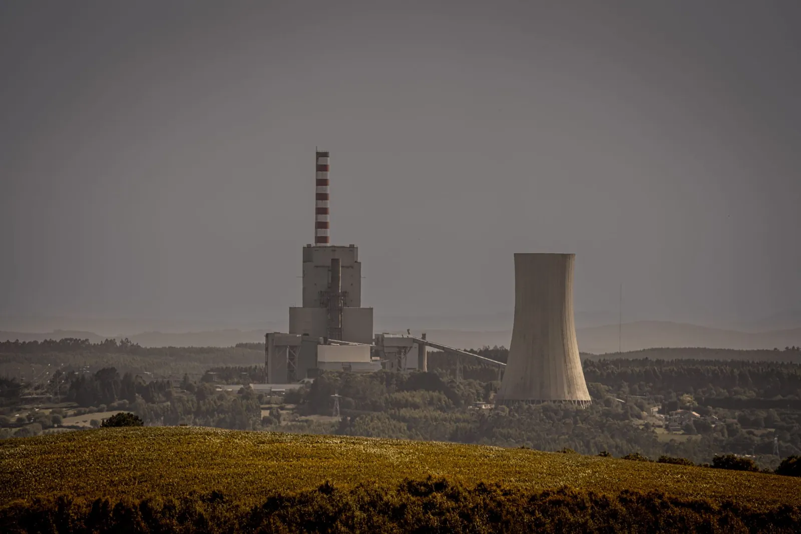 Distant view of a power plant with cooling towers amidst a vast landscape, illustrating energy production. Stock photo illustrating Asian Energy Services' new order story.