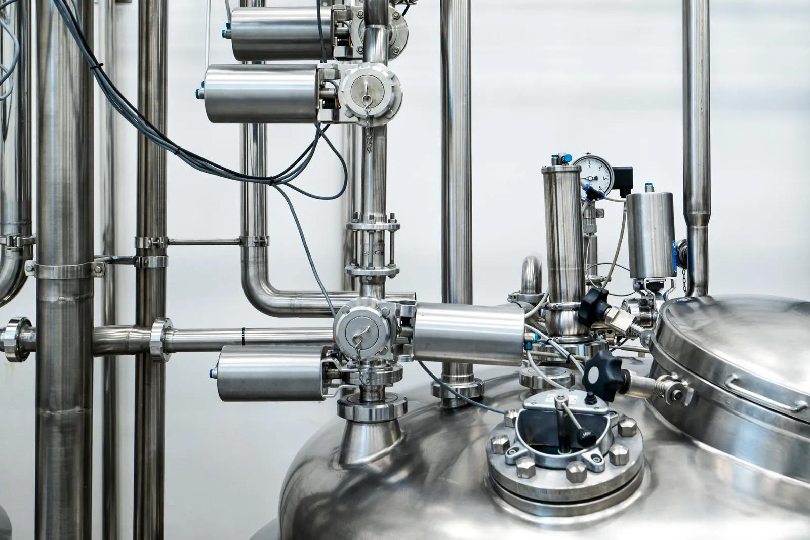 Close-up of stainless steel machinery and pipes in an industrial setting, showcasing modern engineering. Stock photo illustrating Man Industries (India)'s new order story.