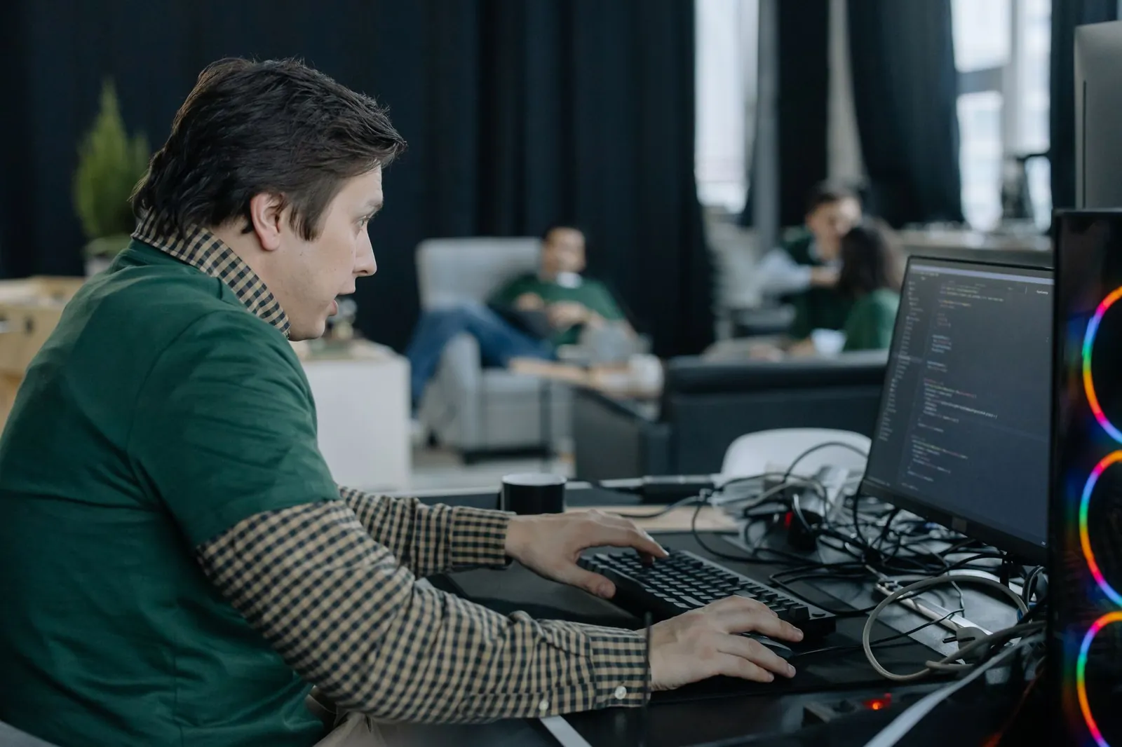 Male programmer concentrating on coding at a computer in a contemporary office setting. Stock photo illustrating Tata Technologies' earning call story.