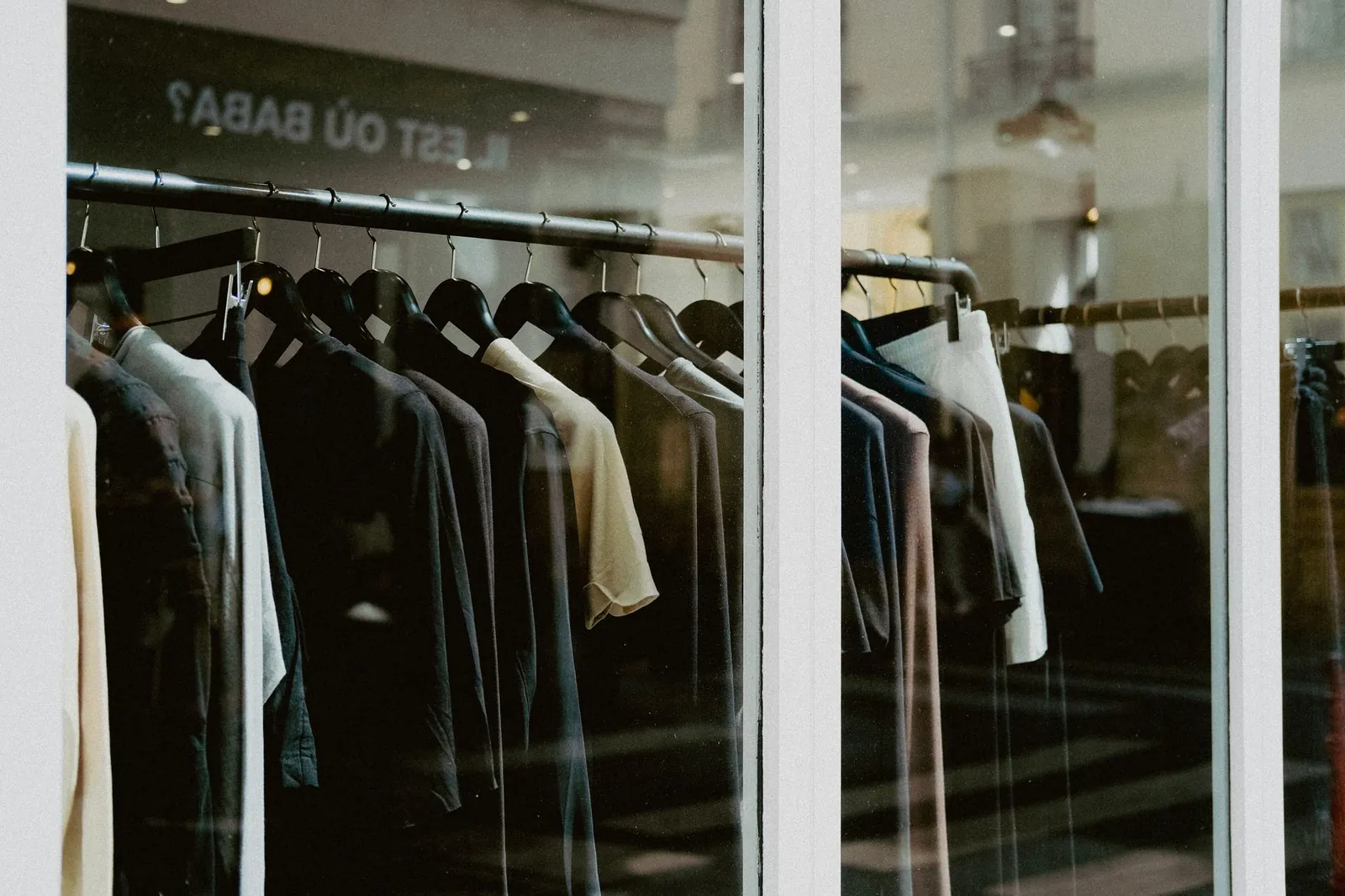 Close-up of clothing on hangers inside a fashion store window. Stock photo illustrating Kewal Kiran Clothing's earning call story.
