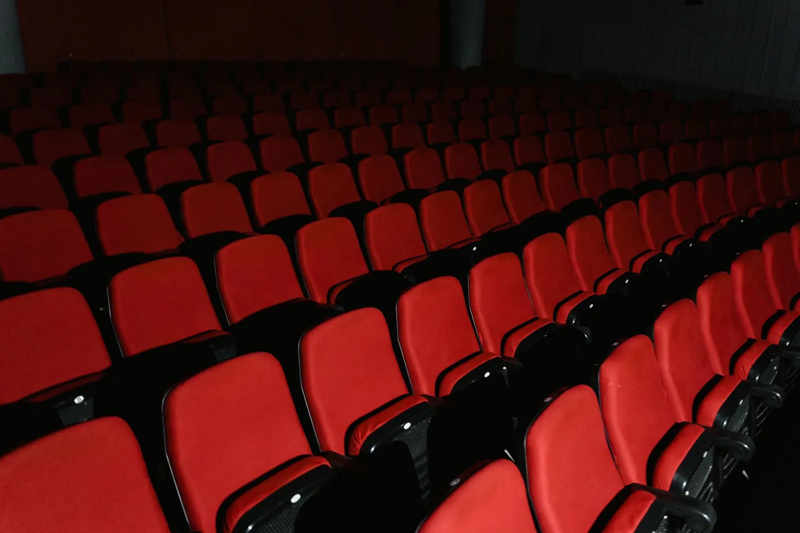 A view of empty red theater seats arranged in rows inside a cinema hall. Stock photo illustrating PVR INOX's financial results story.