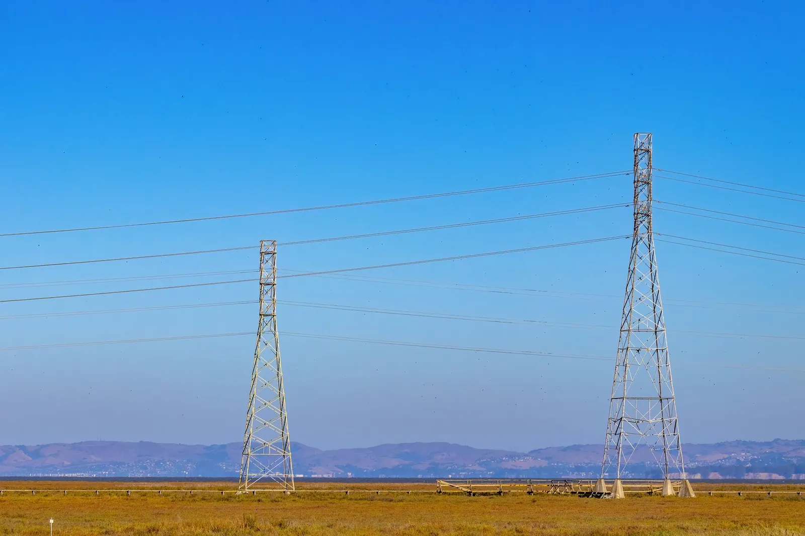 Electric towers and power lines under a clear blue sky in a natural landscape. Stock photo illustrating K2 Infragen's new order story.