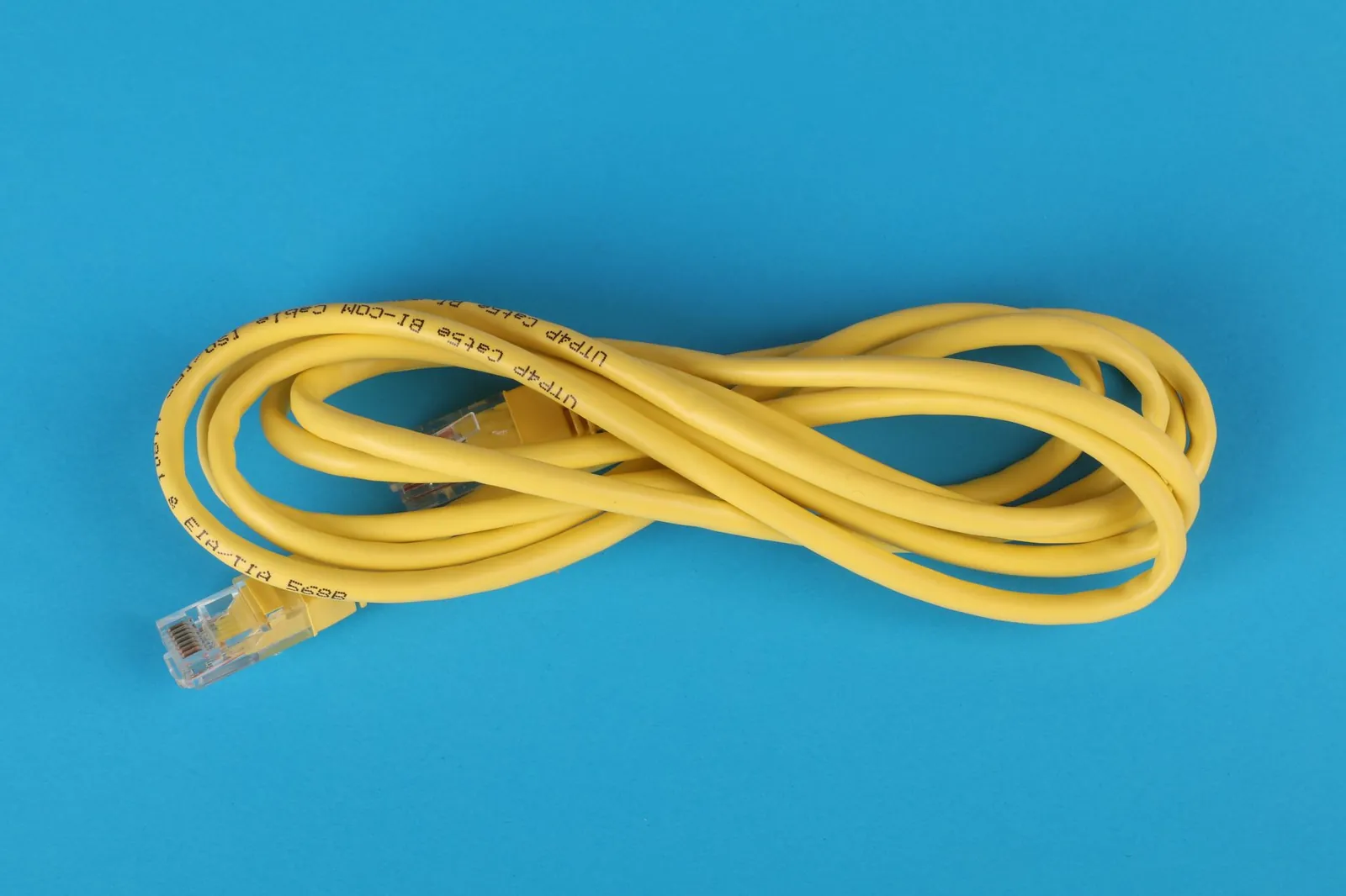 High-angle view of a yellow ethernet cable on a bright blue background. Stock photo illustrating HFCL's product launched story.