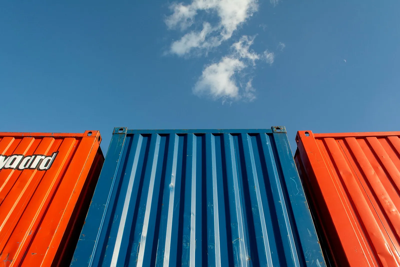 Vibrant red and blue shipping containers under a clear sky, perfect for industrial themes. Stock photo illustrating Waaree Renewable Technologies' new order story.