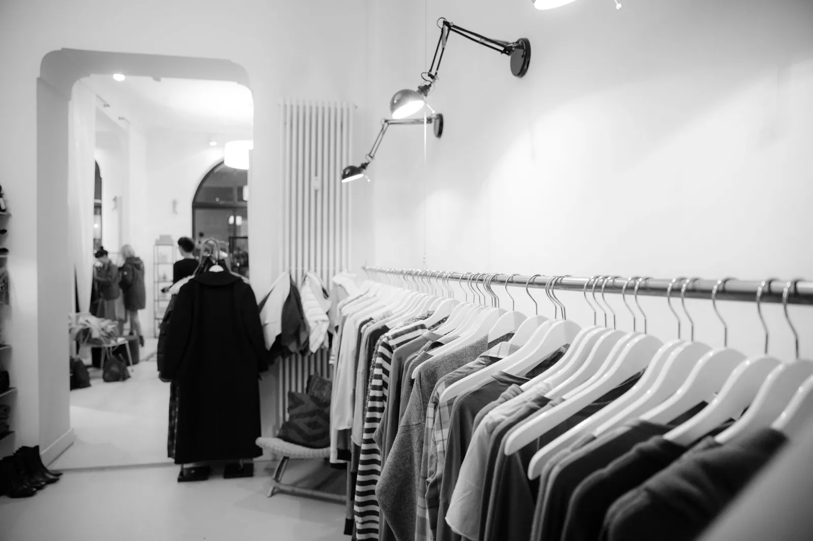 Stylish black and white interior of a boutique with clothes on racks, showcasing modern fashion. Stock photo illustrating V2 Retail's earning call story.