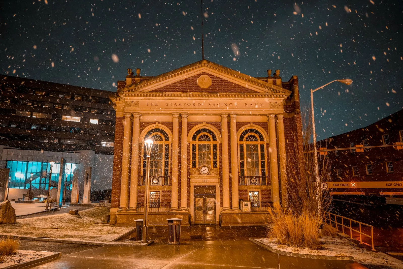 Historic Stamford Savings Bank illuminated at night during a snowfall in Stamford, Connecticut. Stock photo illustrating Ujjivan Small Finance Bank's fund raise story.
