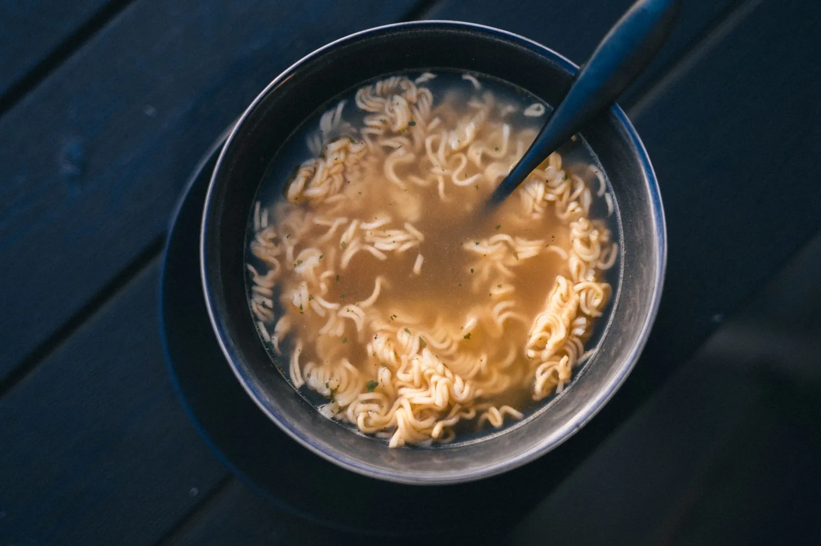 A close-up view of a warm bowl of instant ramen noodles with broth on a dark surface. Stock photo illustrating Rama Vision's product launched story.