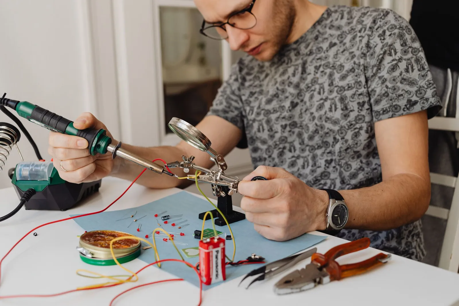 Adult technician soldering electronics with precision tools and equipment indoors. Stock photo illustrating Quality Power Electrical Equipments' earning call story.