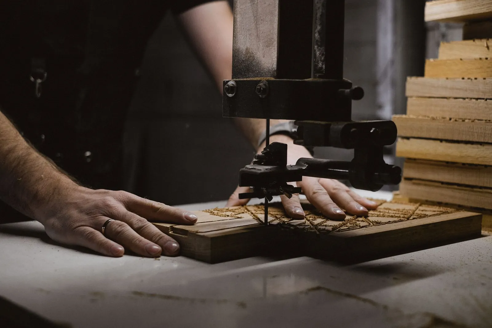 Unrecognizable male master carving patterns on wooden board using special machine while working in professional workshop with stack of wood. Stock photo illustrating Duroply Industries' product launched story.