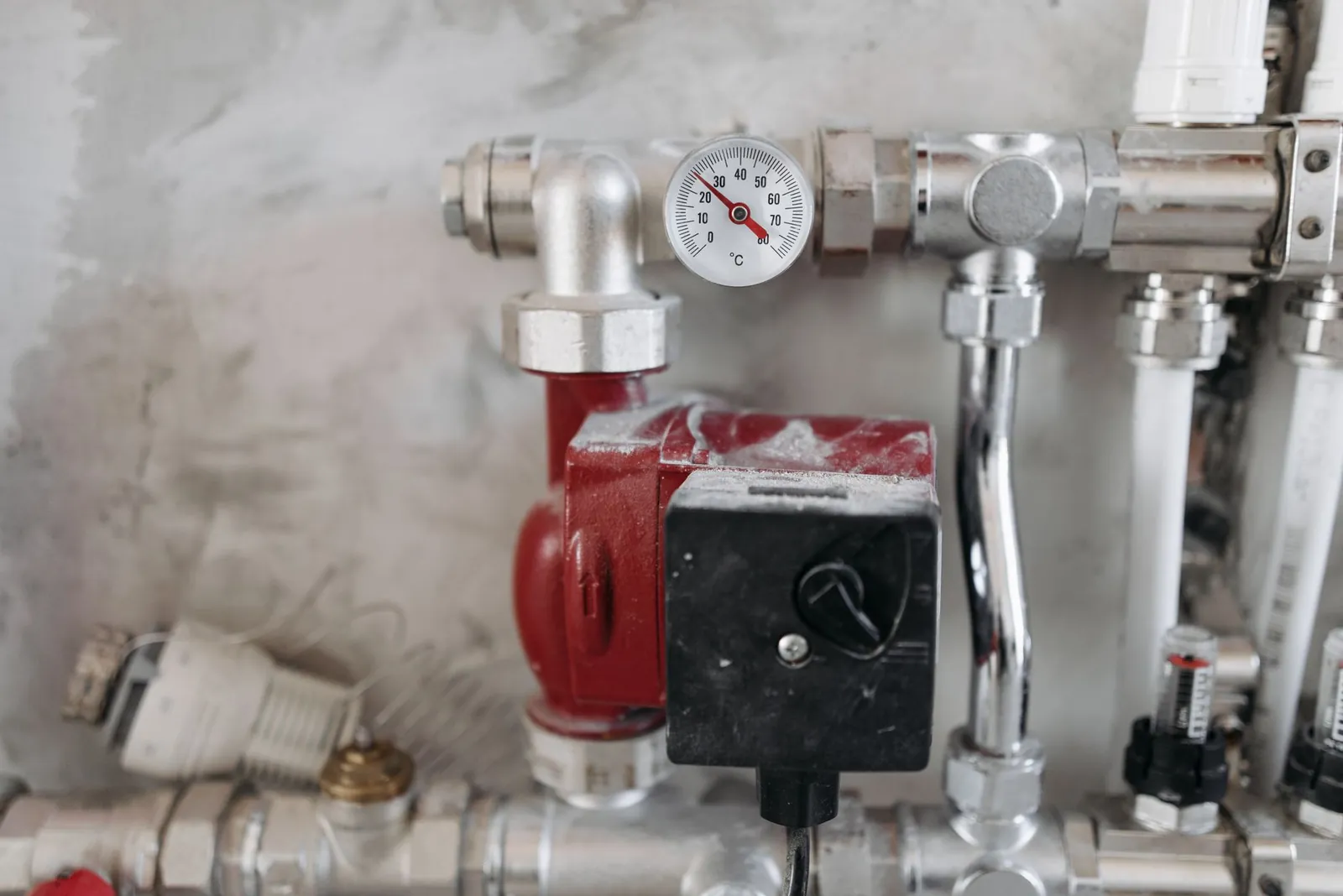 Close-up view of an industrial plumbing system featuring a pressure gauge and steel pipes. Stock photo illustrating Venus Pipes & Tubes' production started story.