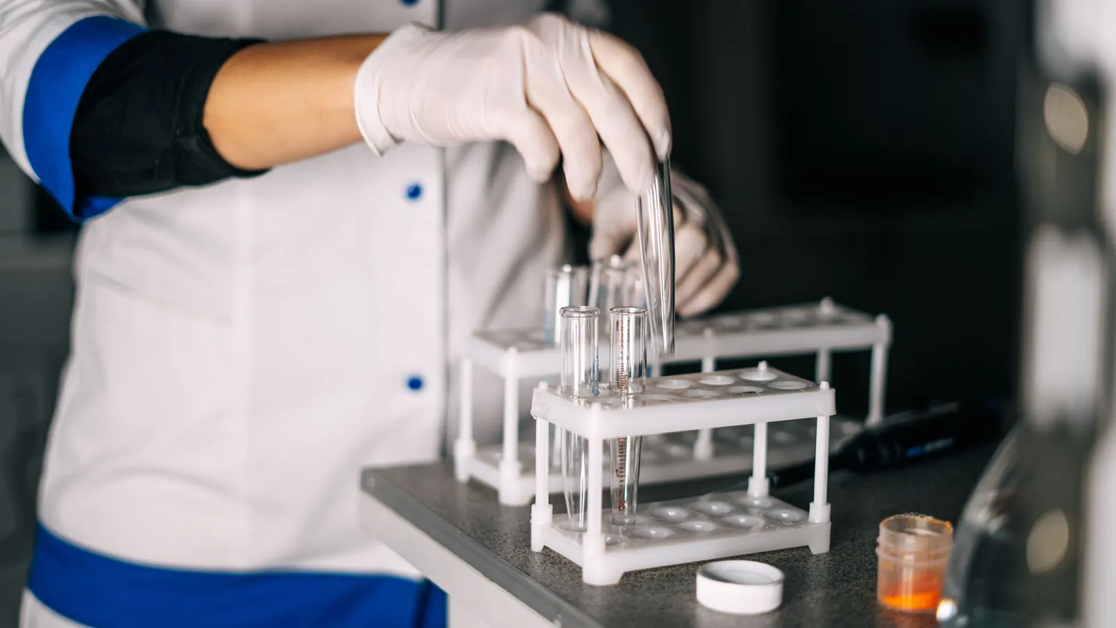 A scientist in a lab coat handling test tubes in a laboratory setting with a focus on equipment. Stock photo illustrating Laurus Labs' financial results story.