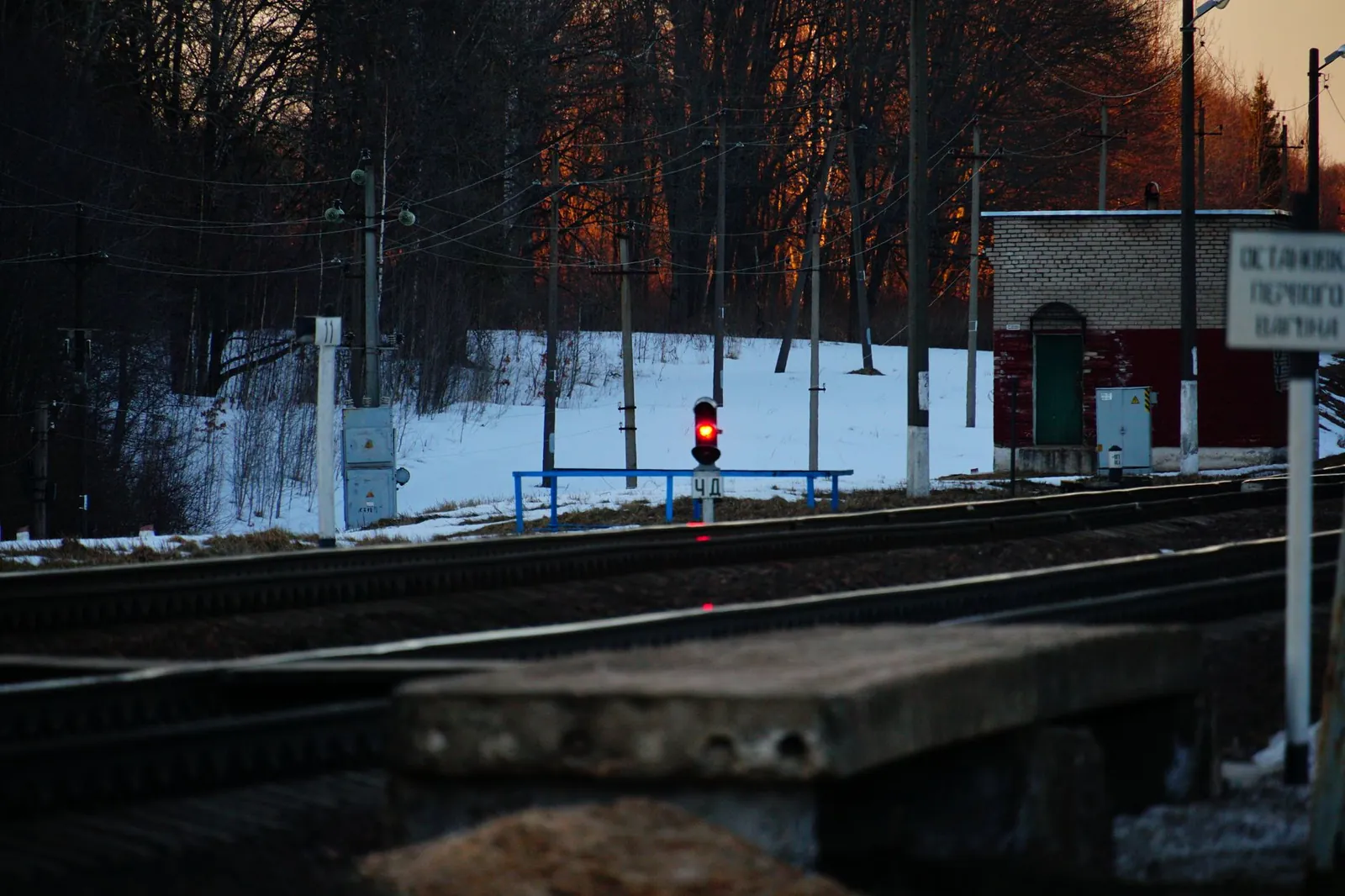 A railway track in winter with a red signal light at sunset, surrounded by snowy trees and infrastructure. Stock photo illustrating E To E Transportation Infrastructure's new order story.