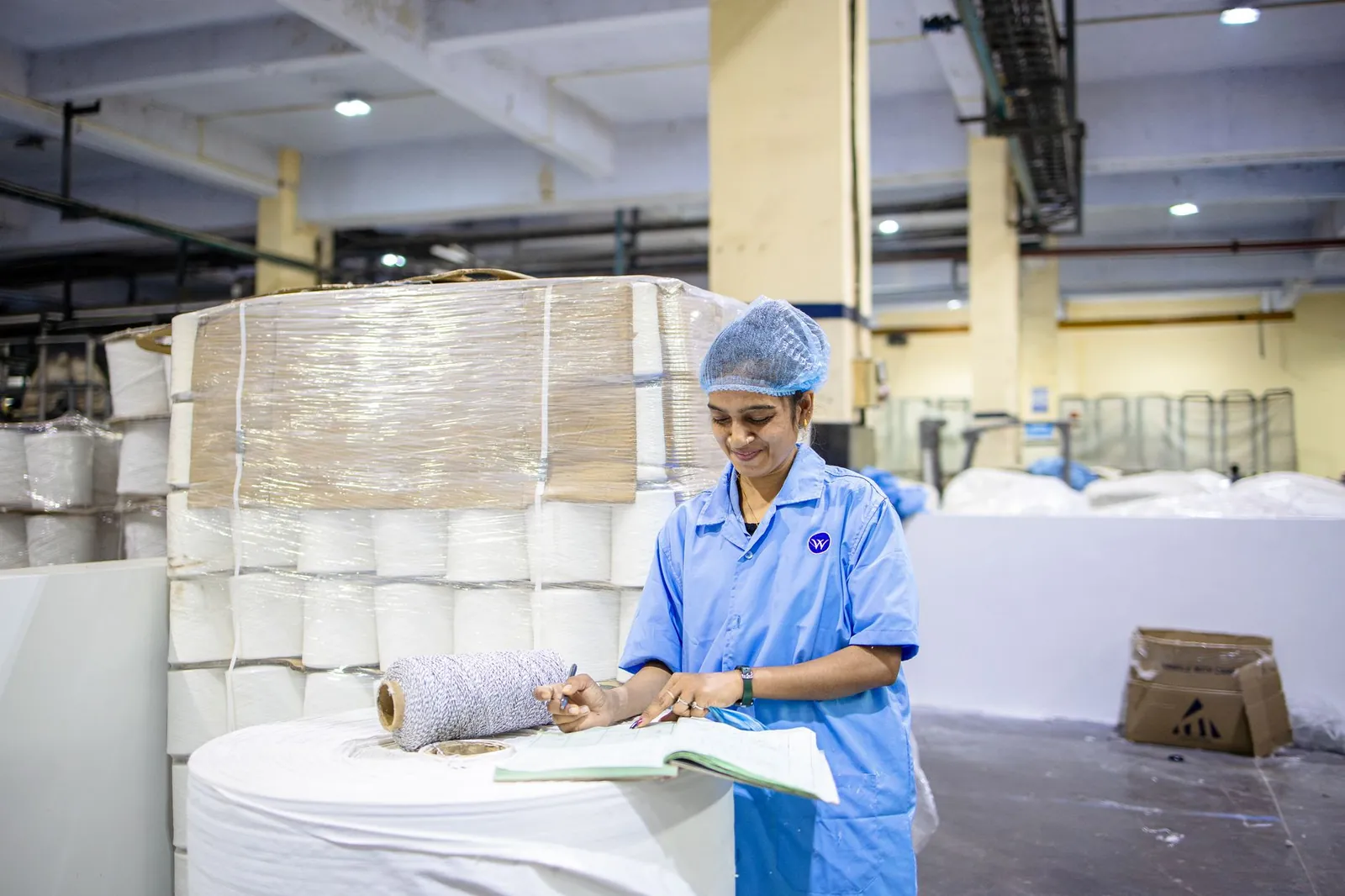 A factory worker records details in a textile manufacturing plant, showcasing industry and precision. Stock photo illustrating Auro Laboratories' regulatory approval story.