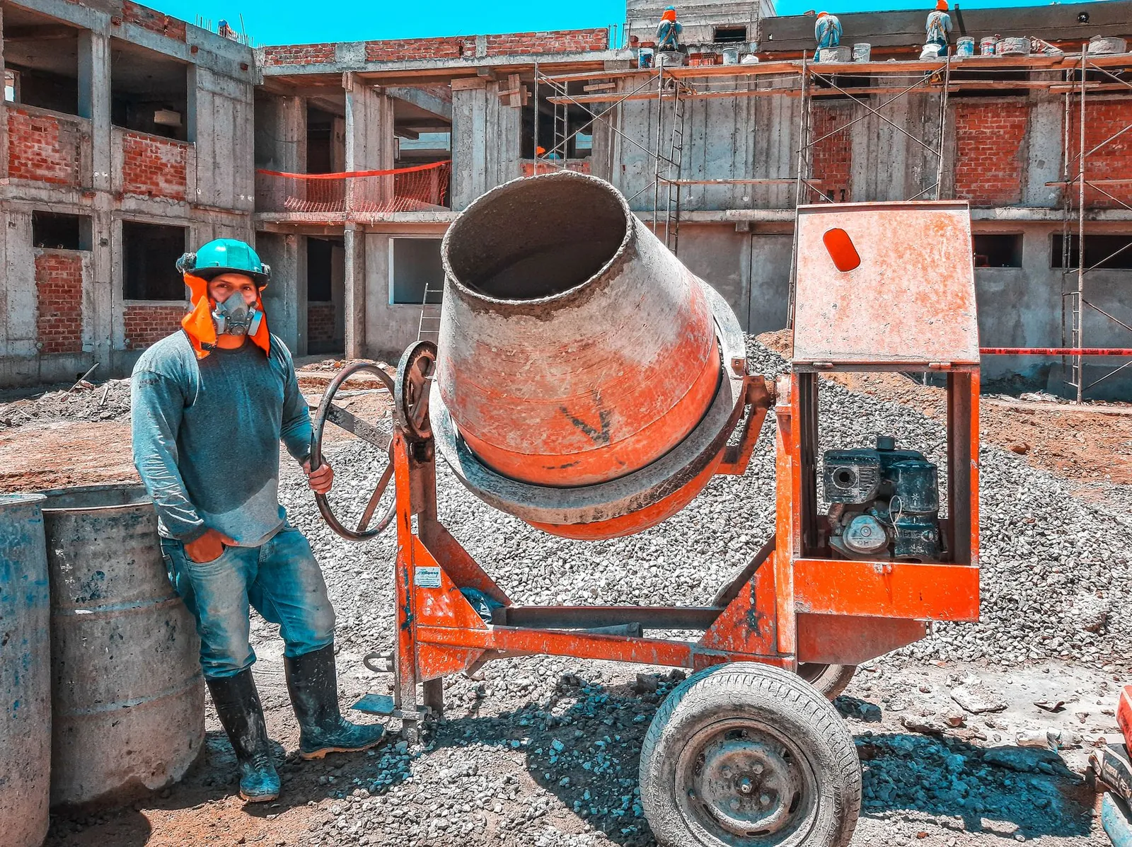 A construction worker operating a concrete mixer at an active building site, emphasizing safety gear. Stock photo illustrating Global Health's expansion story.