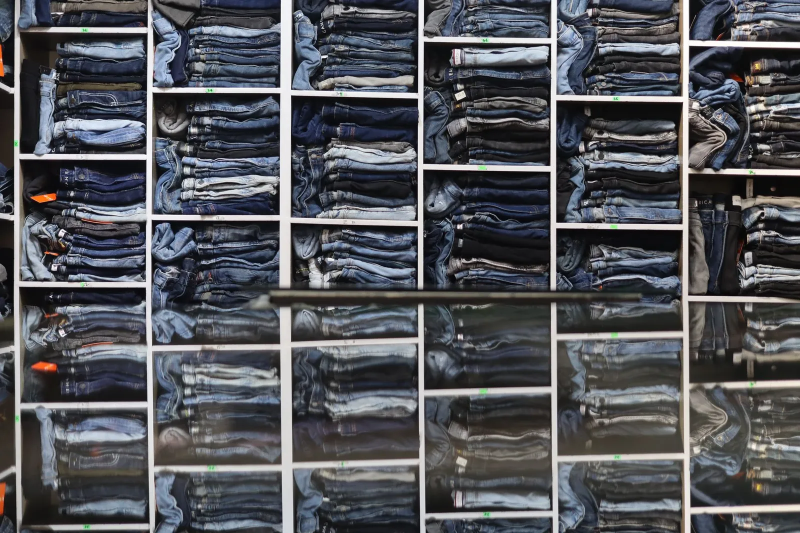 Organized display of folded jeans on shelves in a retail clothing store. Stock photo illustrating T T's expansion story.