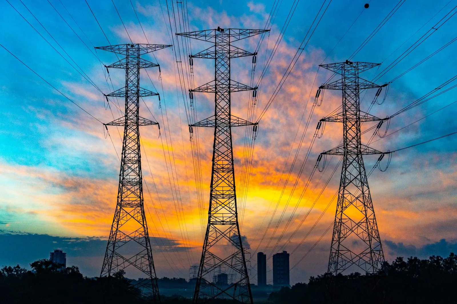 High voltage power lines against a dramatic sunset sky, symbolizing energy and technology. Stock photo illustrating Adani Energy Solutions' new order story.