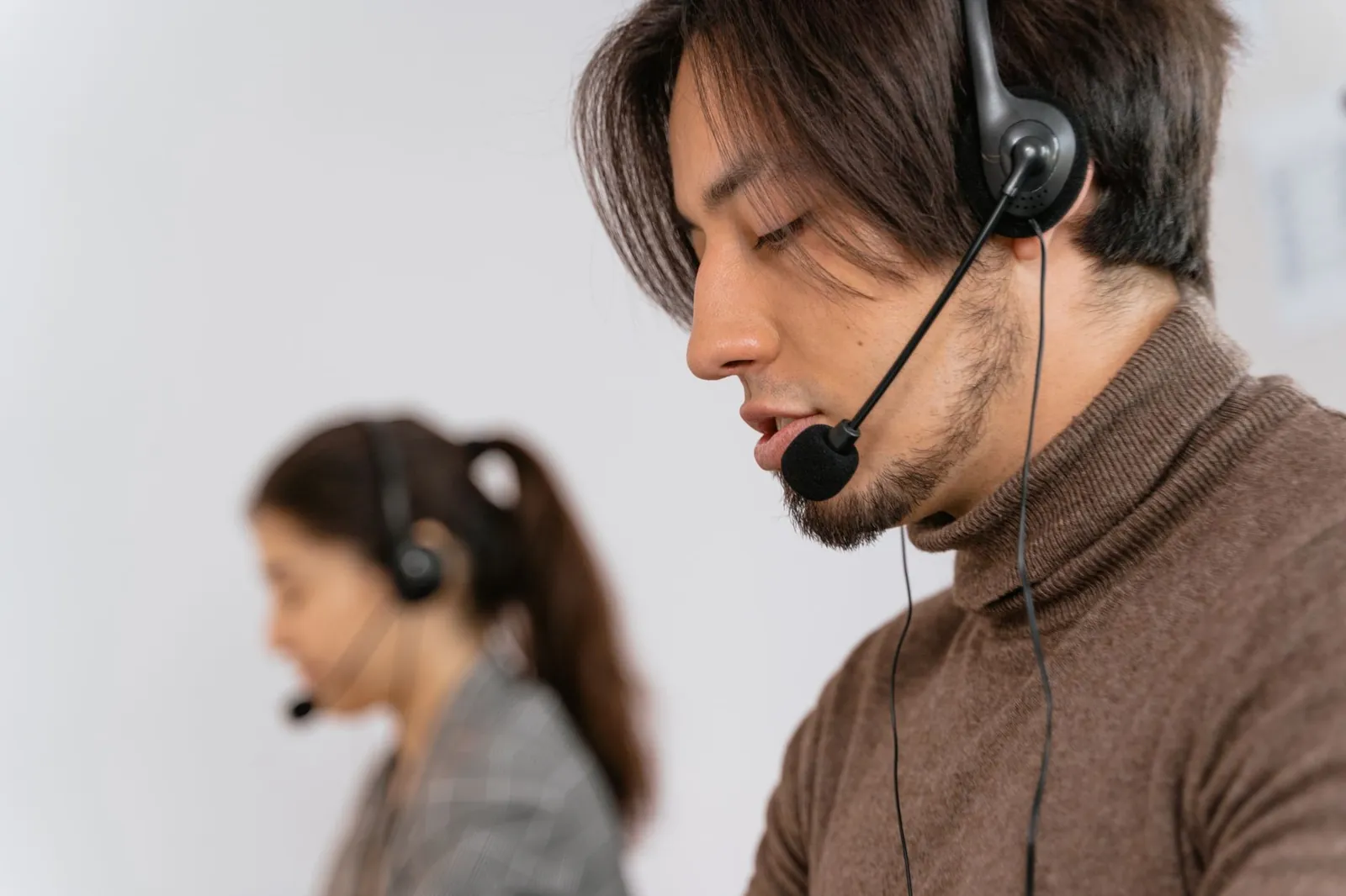 Focused call center employees wearing headsets, assisting customers with exceptional service. Stock photo illustrating One Point One Solutions' earning call story.