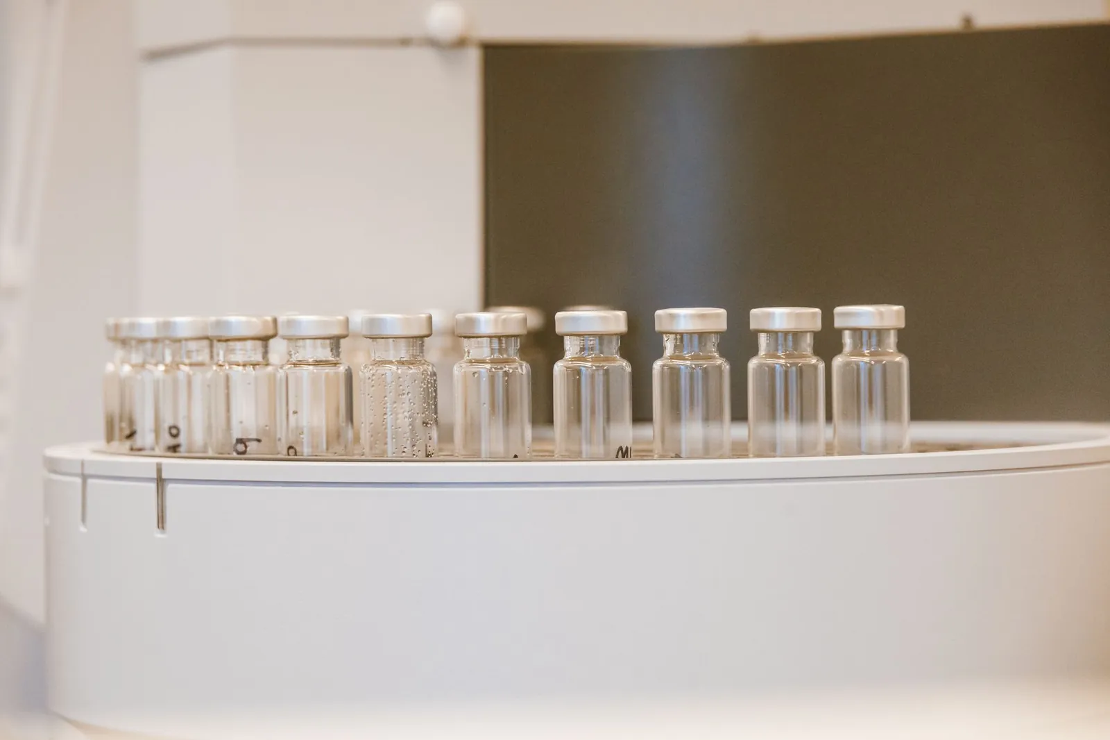 Close-up of empty glass vials arranged in a laboratory environment. Stock photo illustrating Sudarshan Pharma Industries' fund raise story.