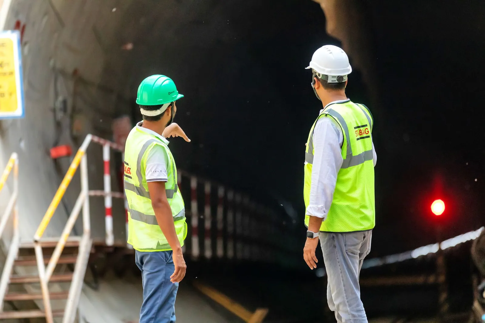 Two construction workers examine a tunnel entrance, highlighting safety and teamwork in infrastructure projects. Stock photo illustrating Almondz Global Securities' new order story.