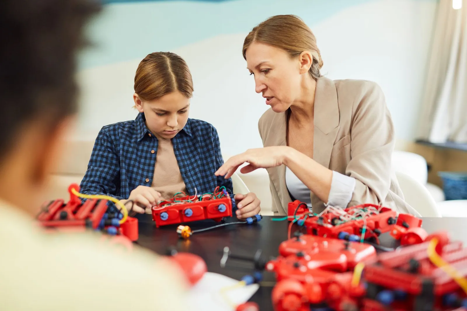 A woman educator helps a young student with a robotics project in a technology classroom. Stock photo illustrating Creative Newtech's product launched story.