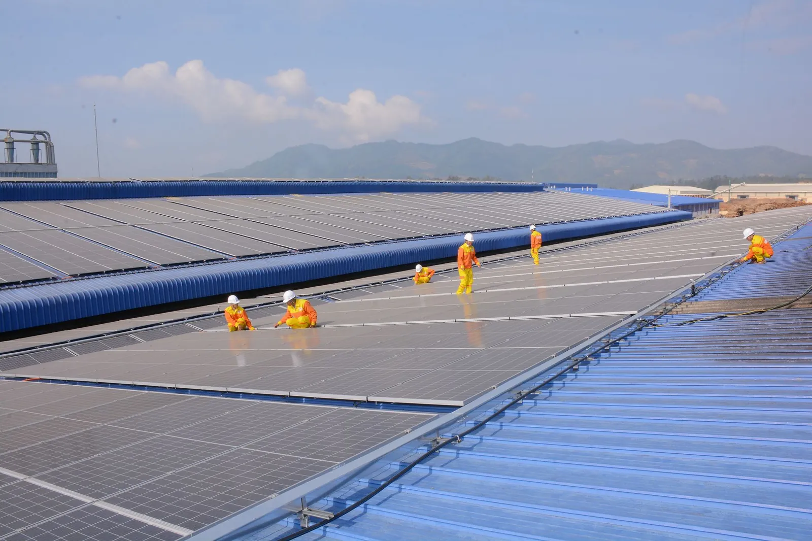 Workers installing solar panels on a large roof, highlighting renewable energy and sustainability. Stock photo illustrating GK Energy's earning call story.