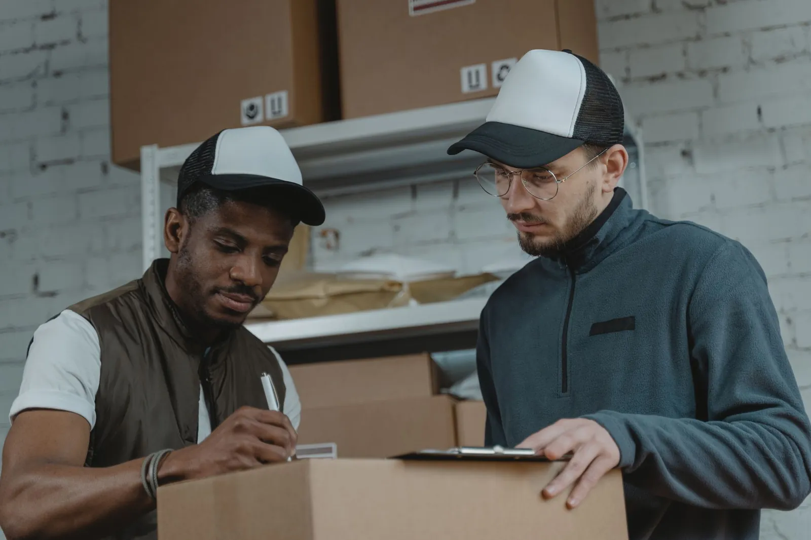 Two couriers working together to process deliveries in a warehouse setting. Stock photo illustrating Unicommerce Esolutions' product launched story.