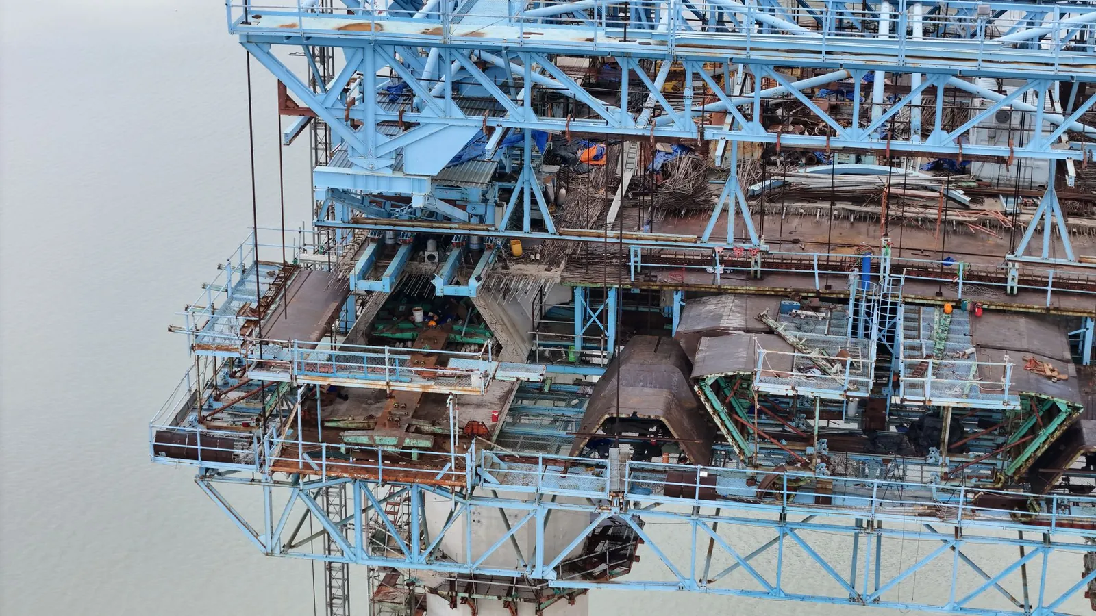 Aerial perspective of an industrial steel structure under construction over water. Stock photo illustrating Shyam Metalics and Energy's expansion story.
