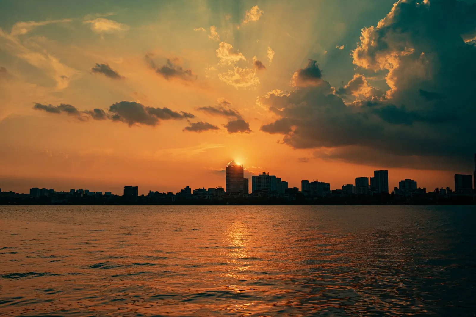 Dramatic sunset over city skyline with silhouettes and vibrant sky reflections. Stock photo illustrating Anand Rathi Wealth's regulatory approval story.