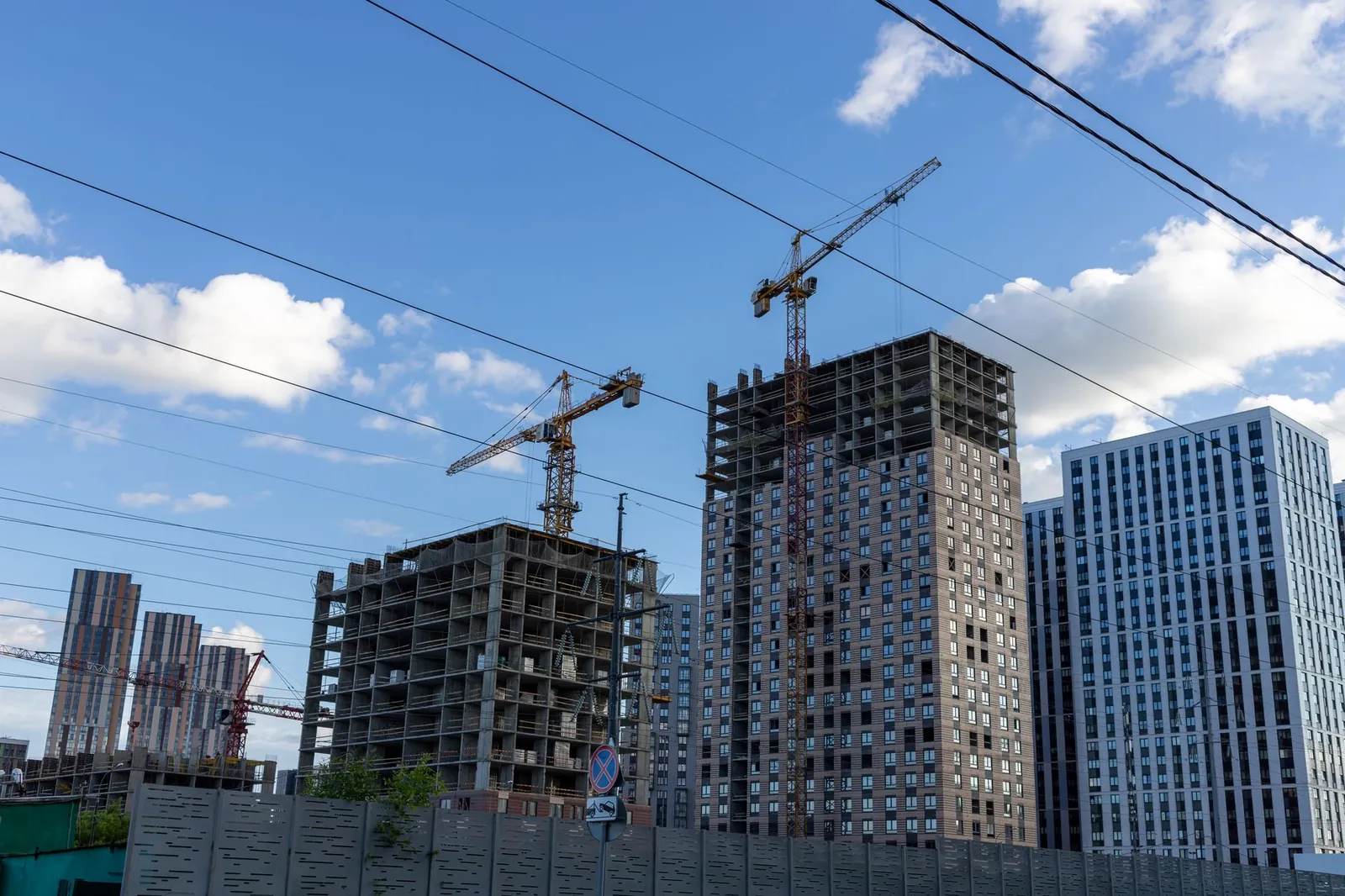 City skyline with modern buildings and construction cranes under a blue sky. Stock photo illustrating B. L. Kashyap and Sons' new order story.