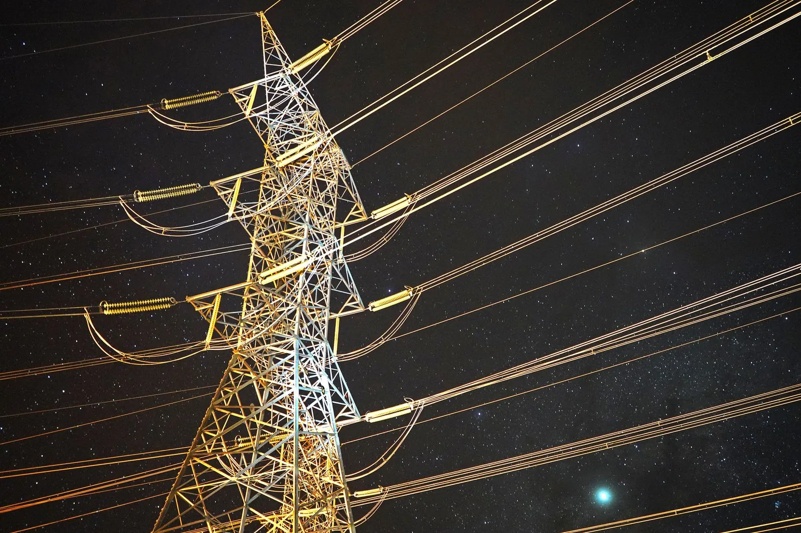 Illuminated power tower against a starry night sky, showcasing energy infrastructure. Stock photo illustrating Swastika Infra's financial results story.