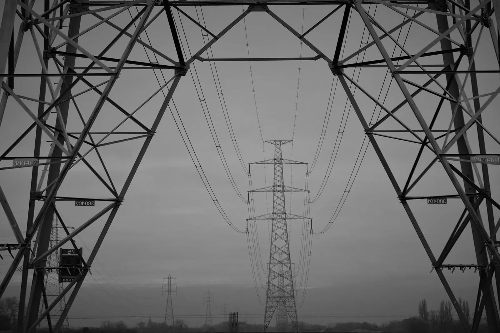 A monochrome view of high voltage electric transmission towers with steel trusses. Stock photo illustrating Skipper's new order story.